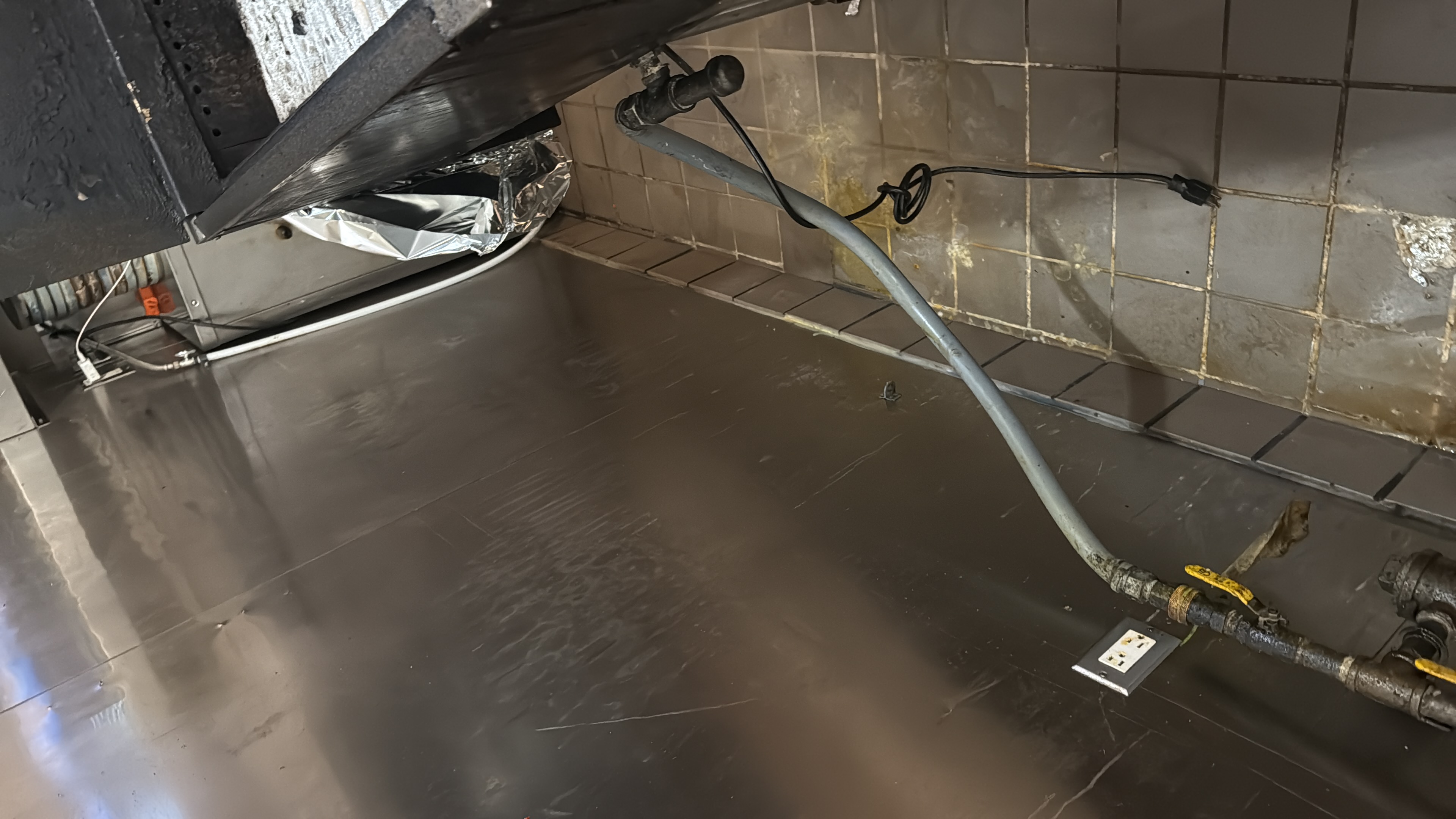 Detailed commercial cleaning behind kitchen equipment